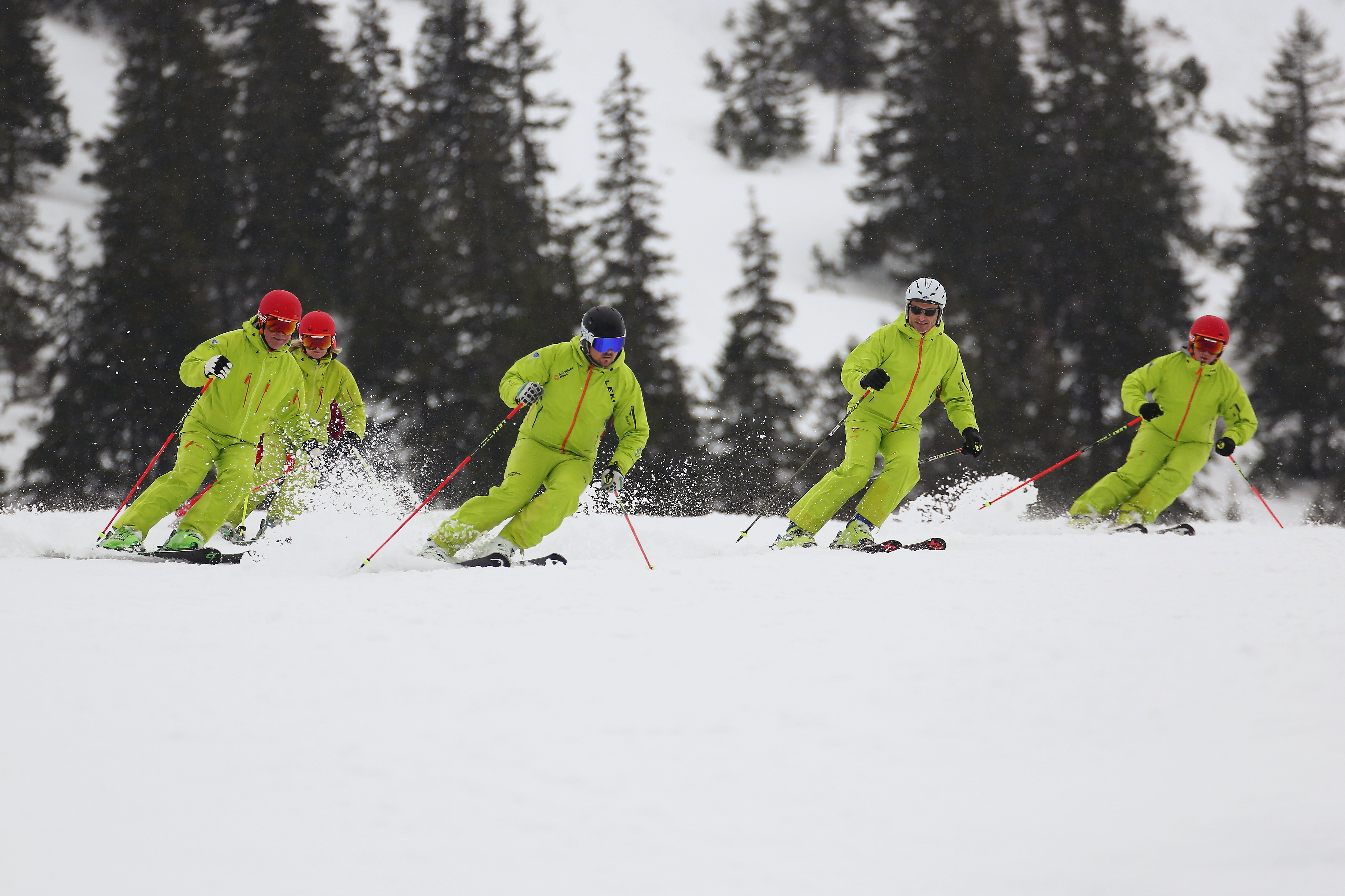Fünf Personen fahren Ski, aufgestellt in einer Formation